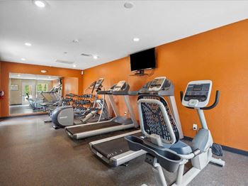 a gym with cardio equipment and weights on the floor